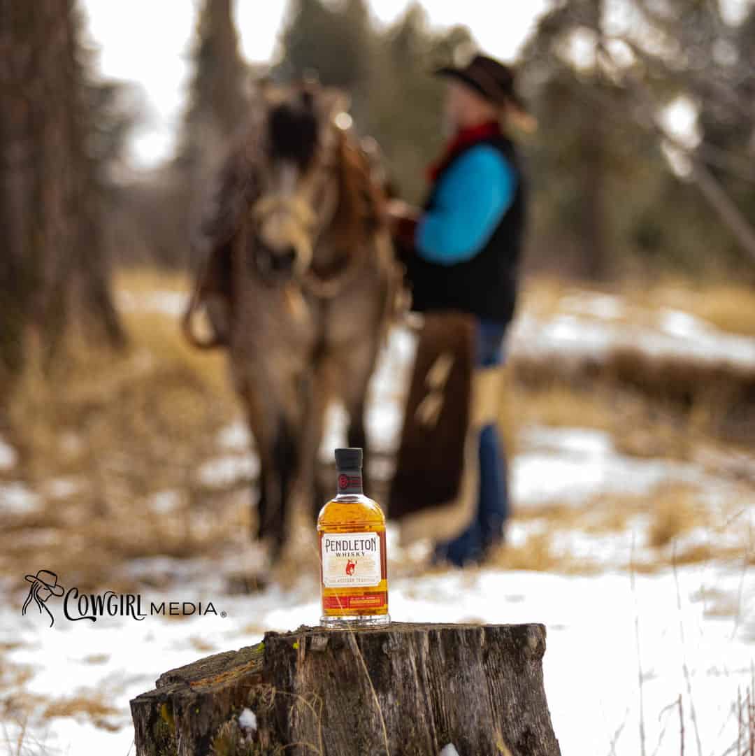Cowboy with buckskin horse and bottle of Pendleton Whisky in foreground