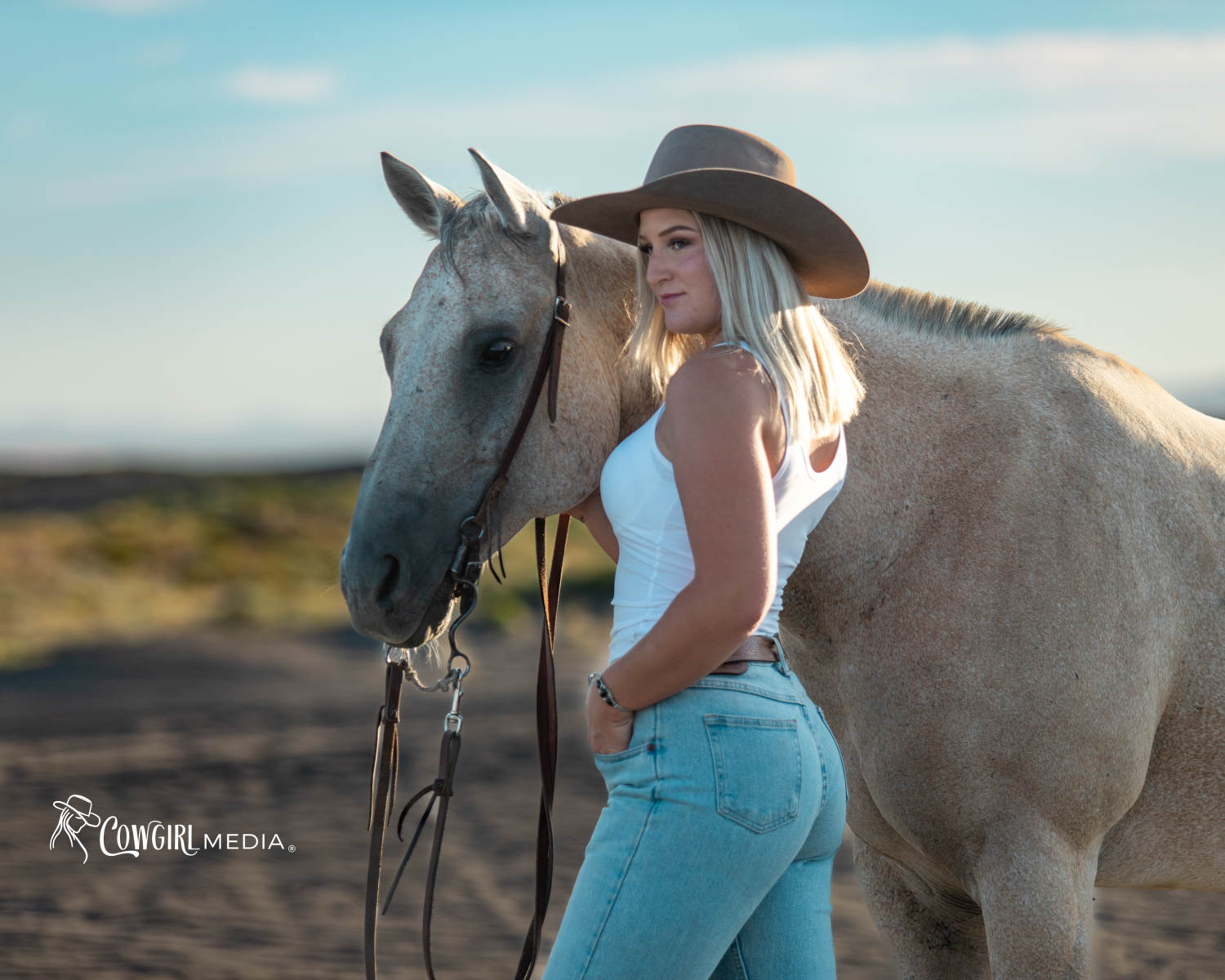 Woman in white tank top standing with roan horse