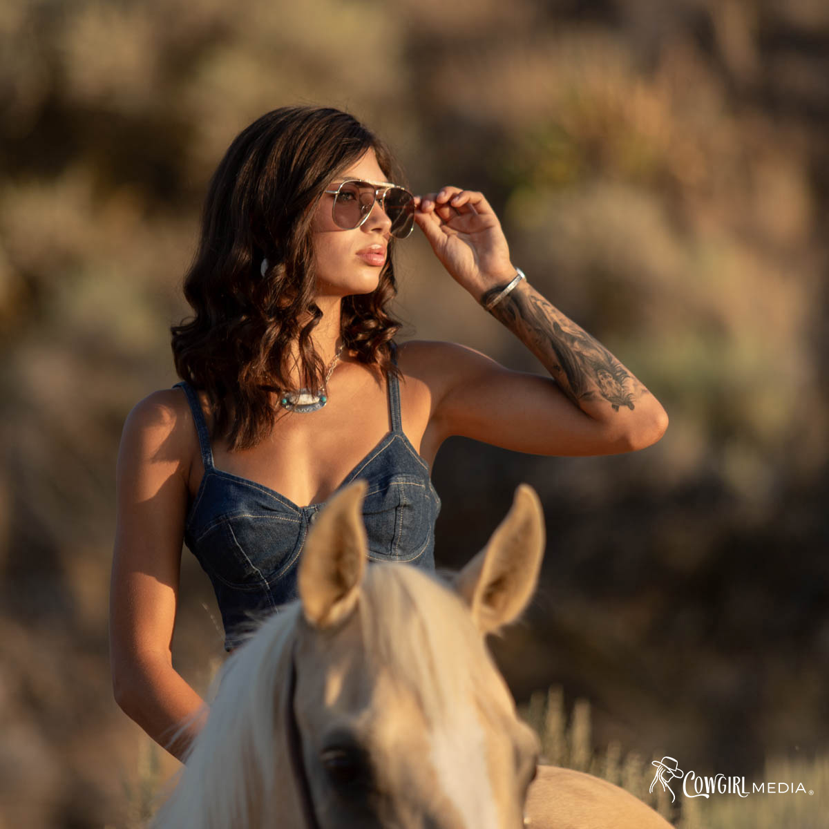 Woman sitting on a horse holding sunglasses