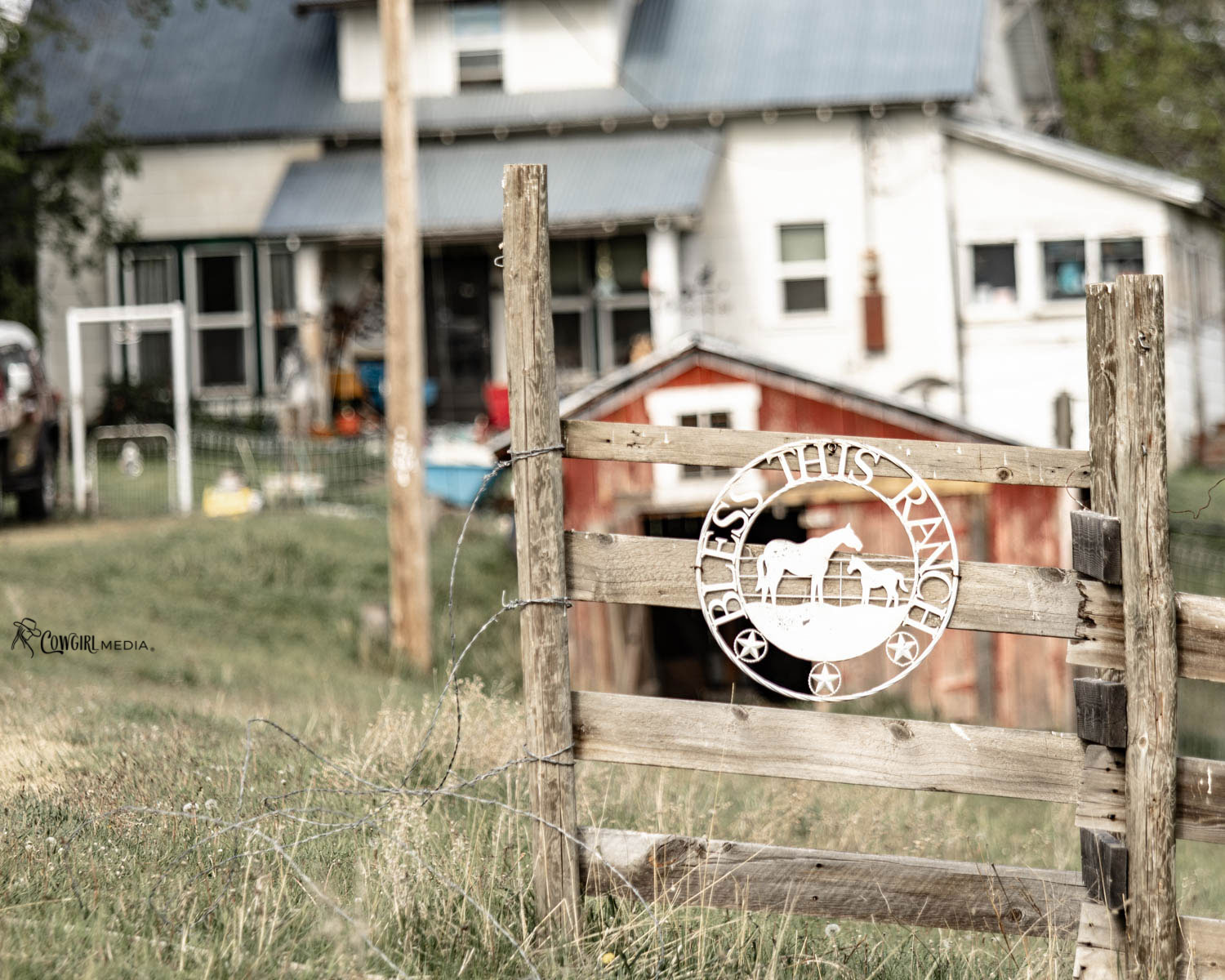 ranch with "Bless this ranch" sign hanging on fence