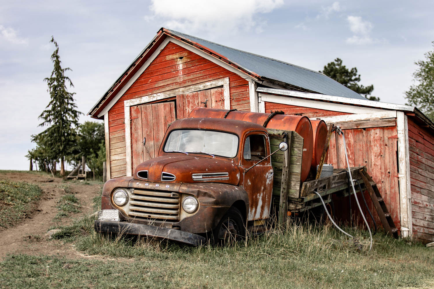 old red ford truck parked in front of a shed