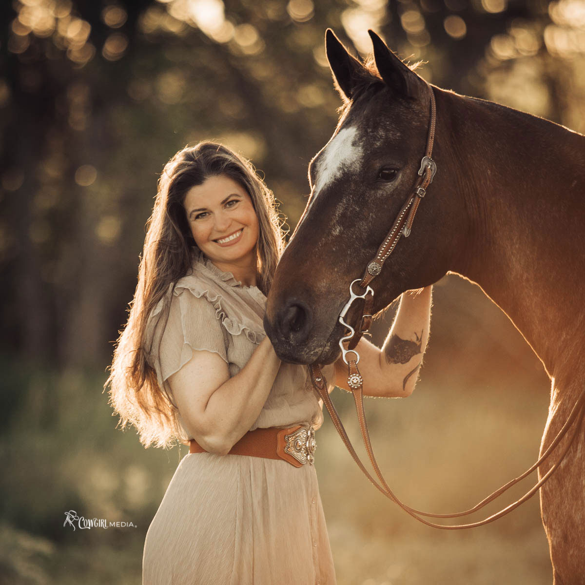 Woman standing with her horse backlit by the sun at golden hour