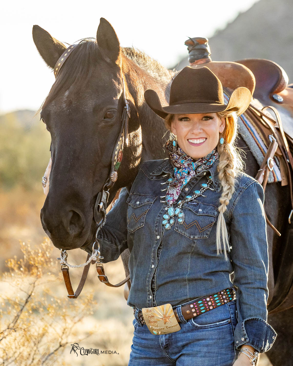 Cowgirl with lots of turquoise posting with her horse in the Arizona desert