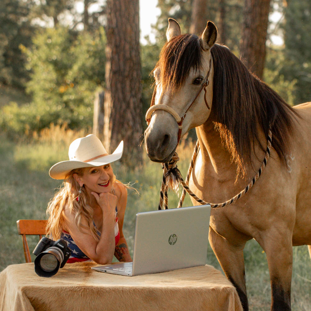Theresa with her buckskin gelding sitting at a table with laptop and camera
