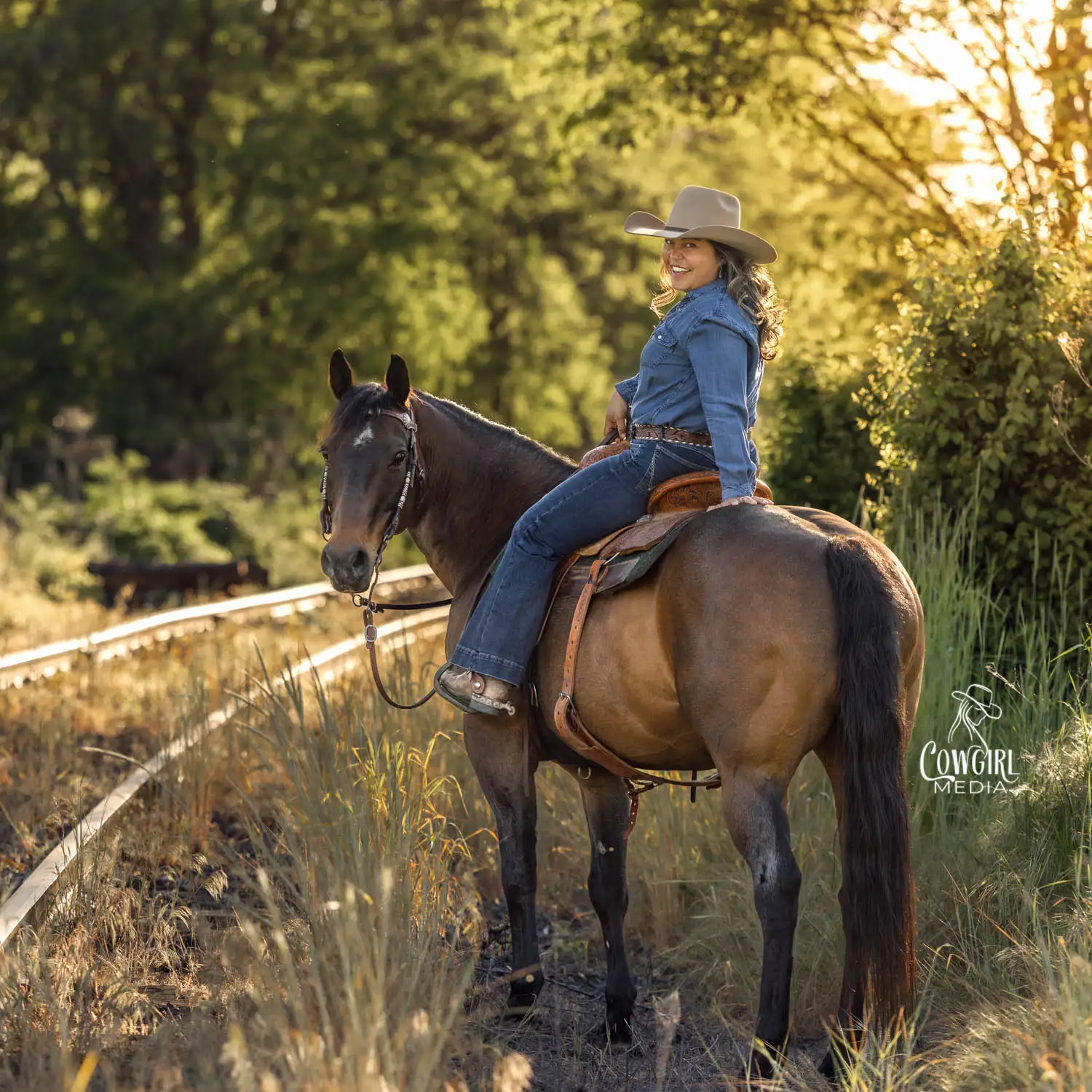 cowgirl sitting on her horse near railroad track look back over her shoulder