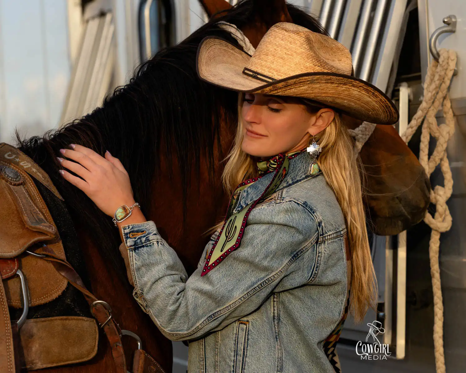 Cowgirl wearing beautiful turquoise western jewelry, standing next to her horse