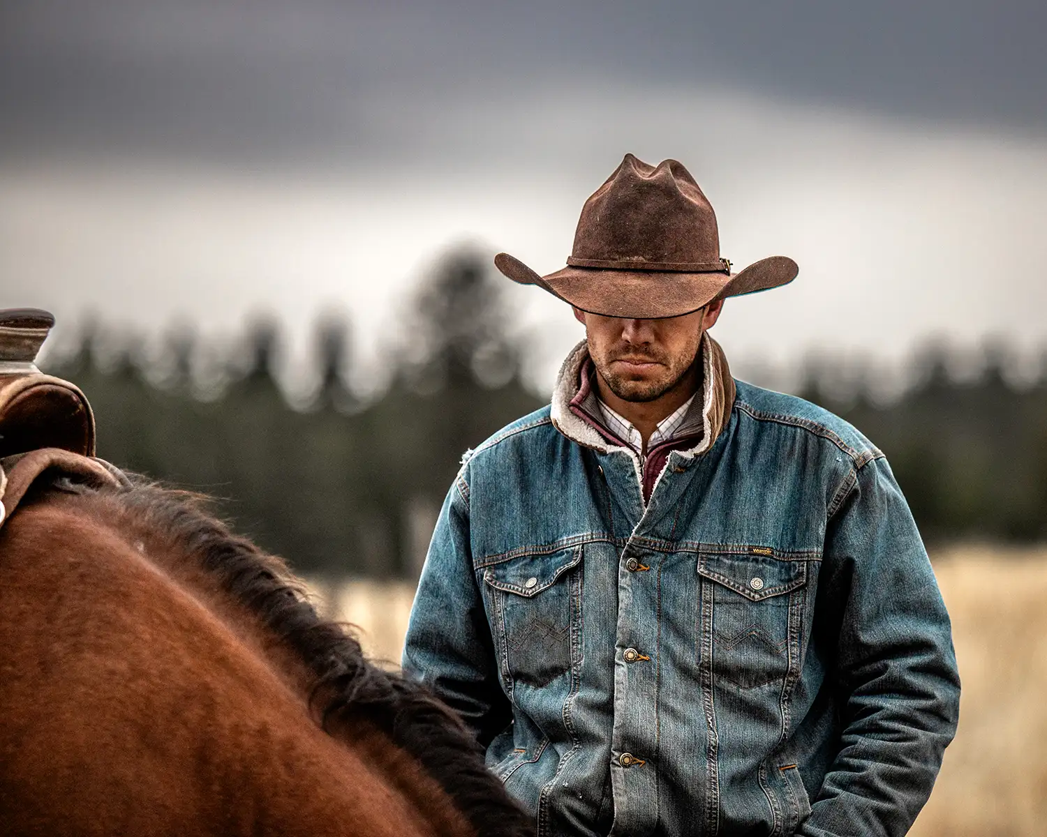 Cowboy standing next to his horse after the fall gather